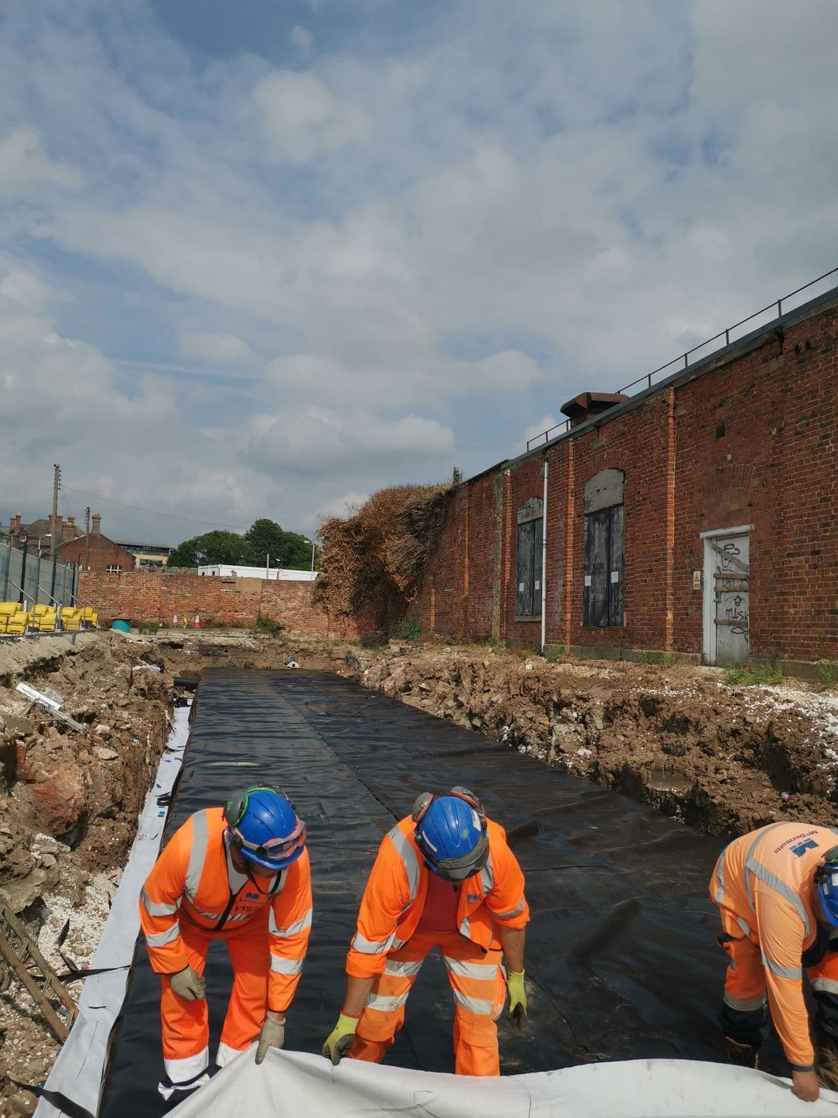 Aquatech crew laying membrane in the tank excavation beside the railway buildings at York station
